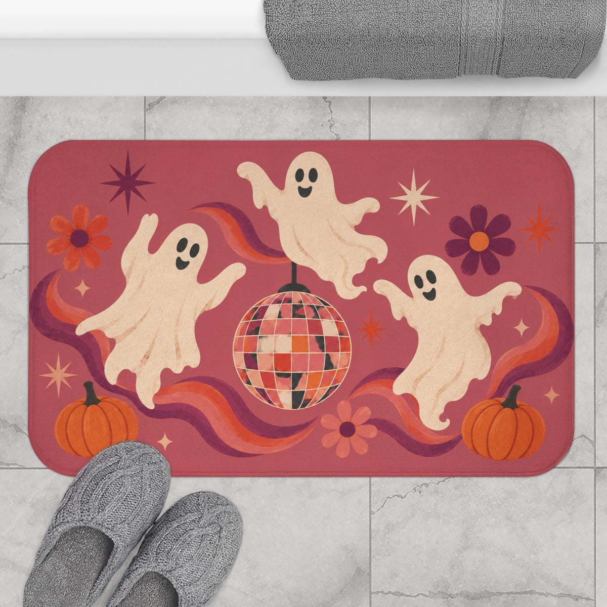 AmazerBath Halloween bath mat featuring dancing ghosts, disco ball, and pumpkins placed on light bathroom tile beside a bathtub.