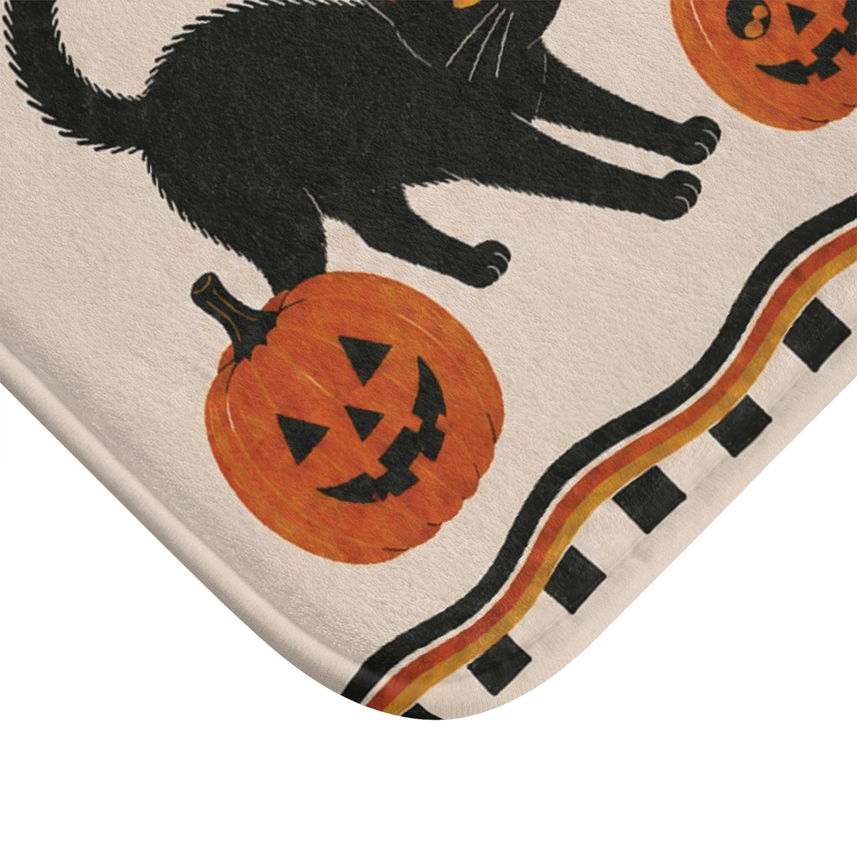 AmazerBath Halloween bath mat corner with black cats and jack-o'-lanterns on cream, vivid print, soft texture, and a bound edge.