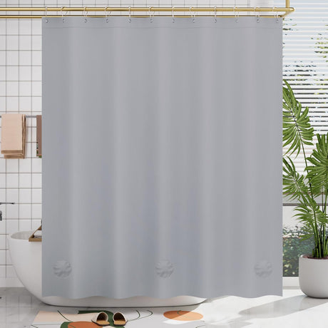 Gray shower curtain liner in a bathroom with a plant and bathtub.