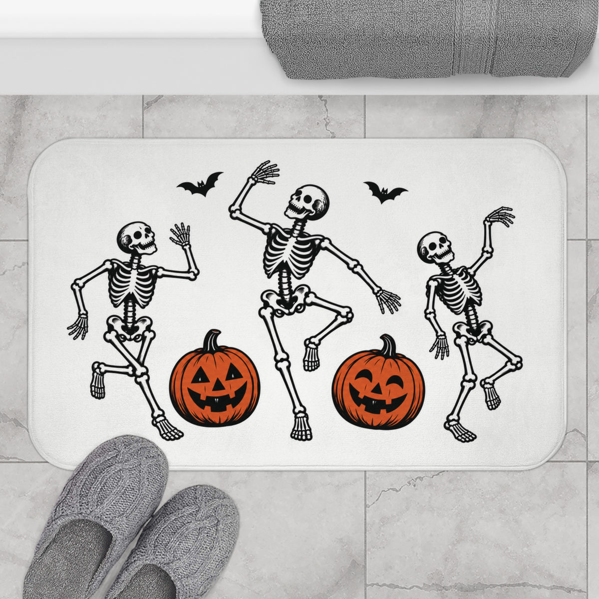 AmazerBath Halloween bath mat featuring dancing skeletons with jack-o'-lanterns placed on light bathroom tile beside a bathtub.