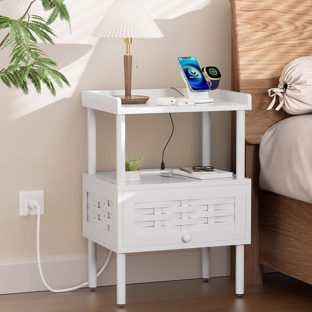 White nightstand with lamp, phone, and books next to a bed
