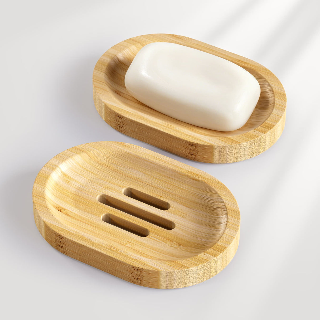 Two bamboo wooden soap dishes with a bar of soap on a light gray background