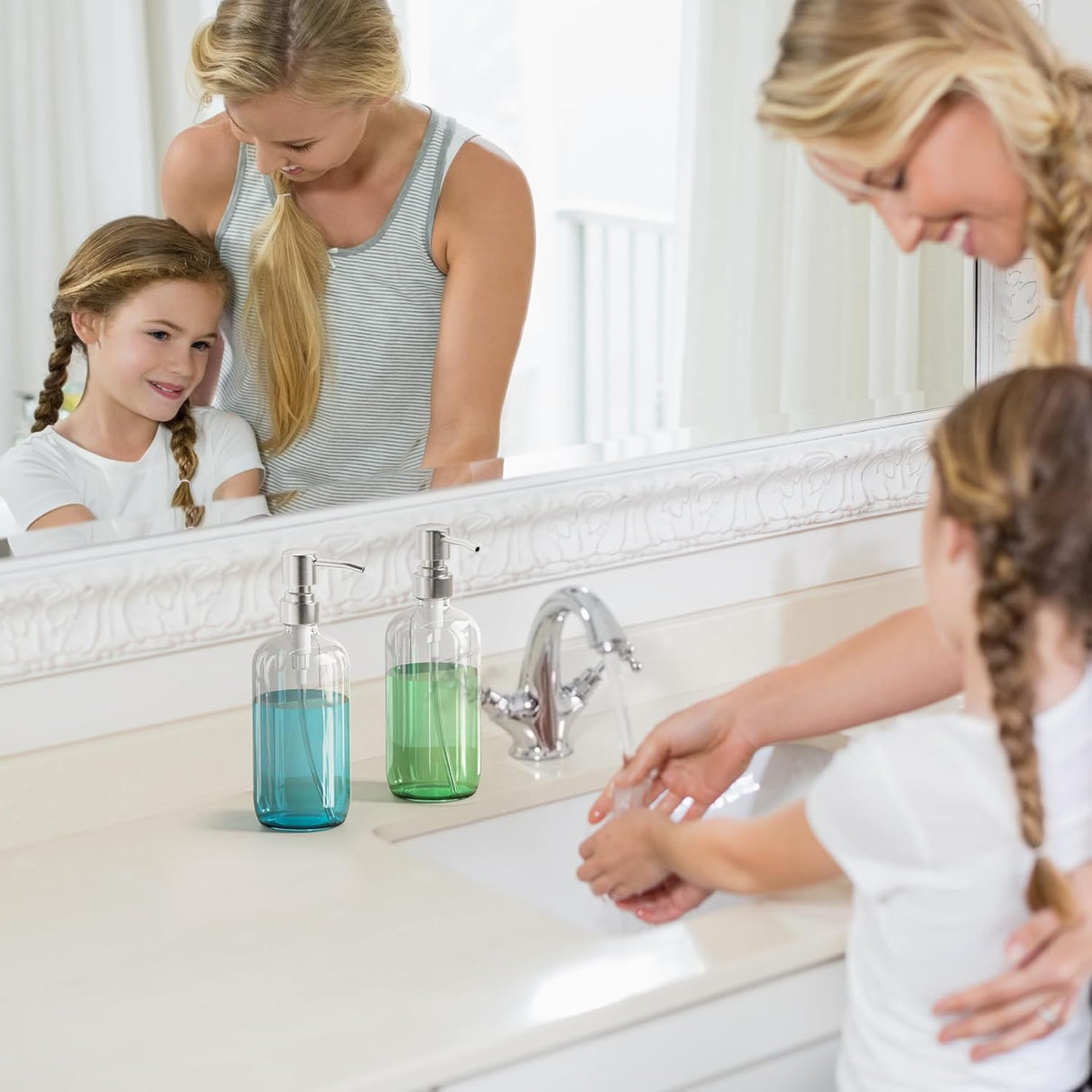 Two women and a young girl washing hands in a bathroom sink with soap dispensers.