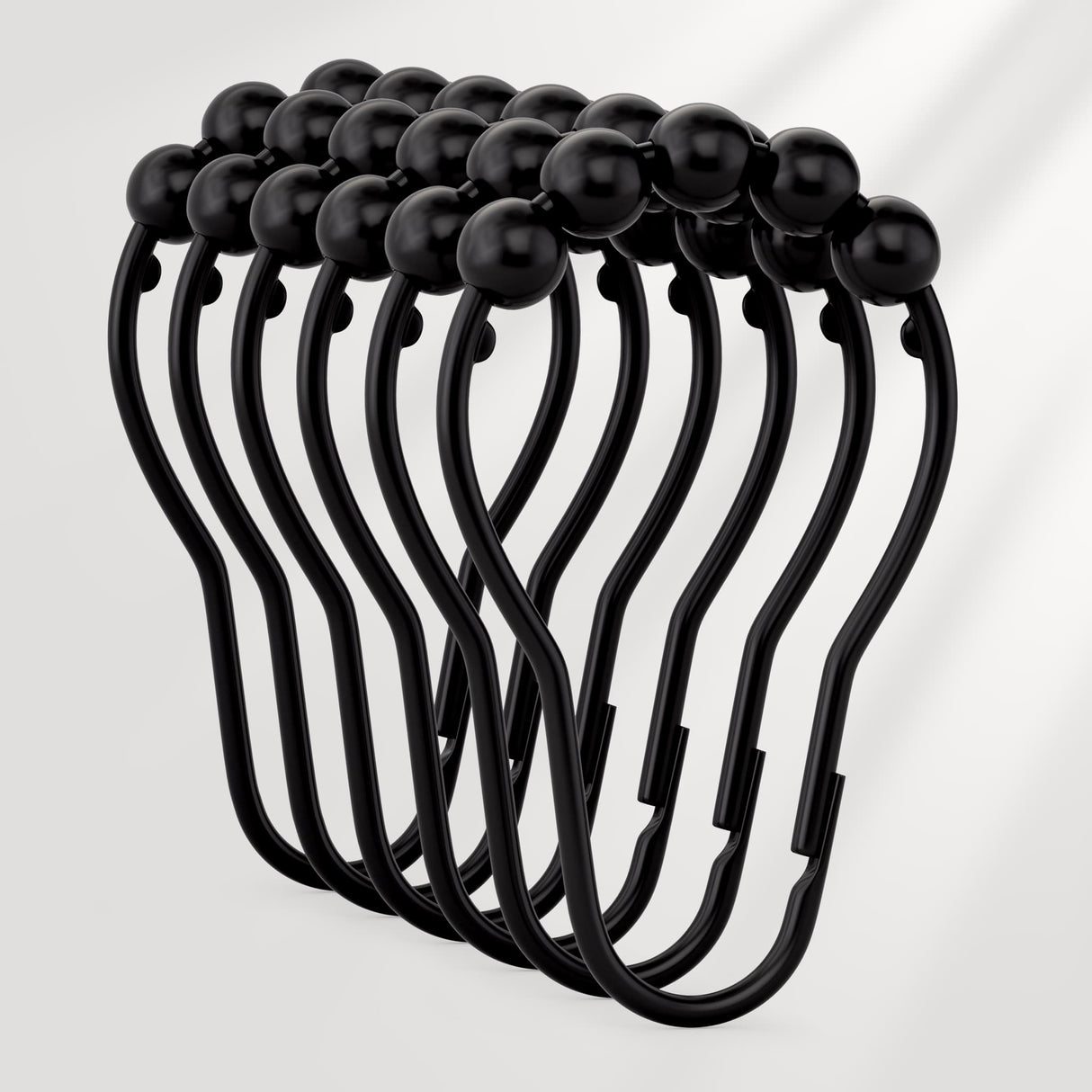 Set of black curtain hooks on a light gray background