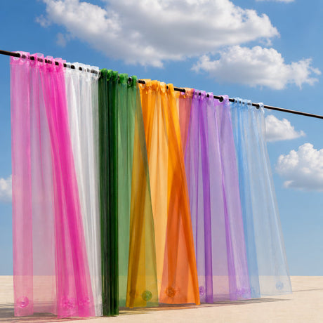 Colorful sheer curtains hanging against a blue sky with clouds