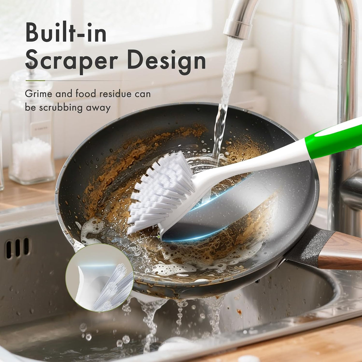 Cleaning brush with built-in scraper being used on a dirty pan in a kitchen sink.