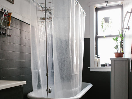 Clean shower curtain and liner hanging to dry in a bright bathroom