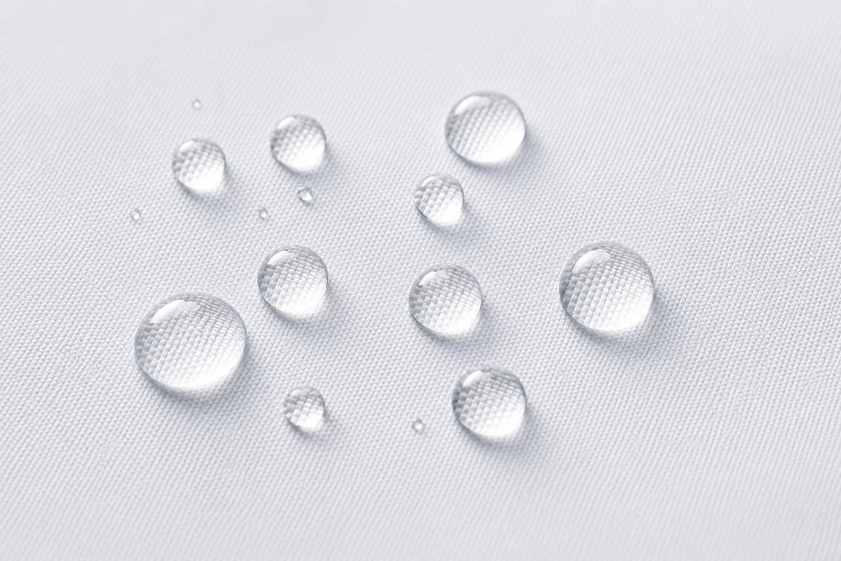 Close-up of white fabric shower curtain liner with water droplets showing water resistant surface and textured material.
