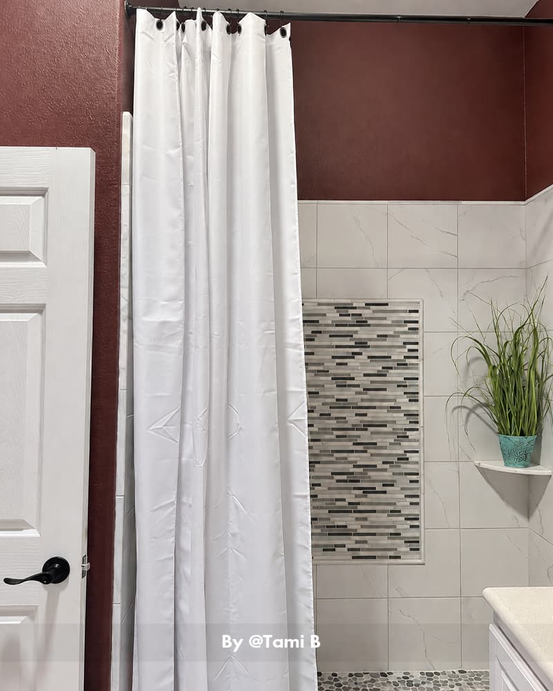 AmazerBath white 120 GSM fabric shower curtain liner displayed in a bathroom with burgundy walls and mosaic tile.