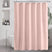 Pink shower curtain in a bathroom setting with a freestanding bathtub and decorative elements.