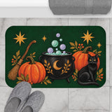 AmazerBath Halloween bath mat featuring green pumpkins, cauldron, black cat, and broom placed on light bathroom tile beside a bathtub.