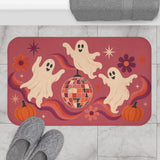 AmazerBath Halloween bath mat featuring dancing ghosts, disco ball, and pumpkins placed on light bathroom tile beside a bathtub.