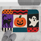 AmazerBath Halloween bath mat featuring patchwork cat, ghost, and jack-o'-lantern placed on light bathroom tile beside a bathtub.