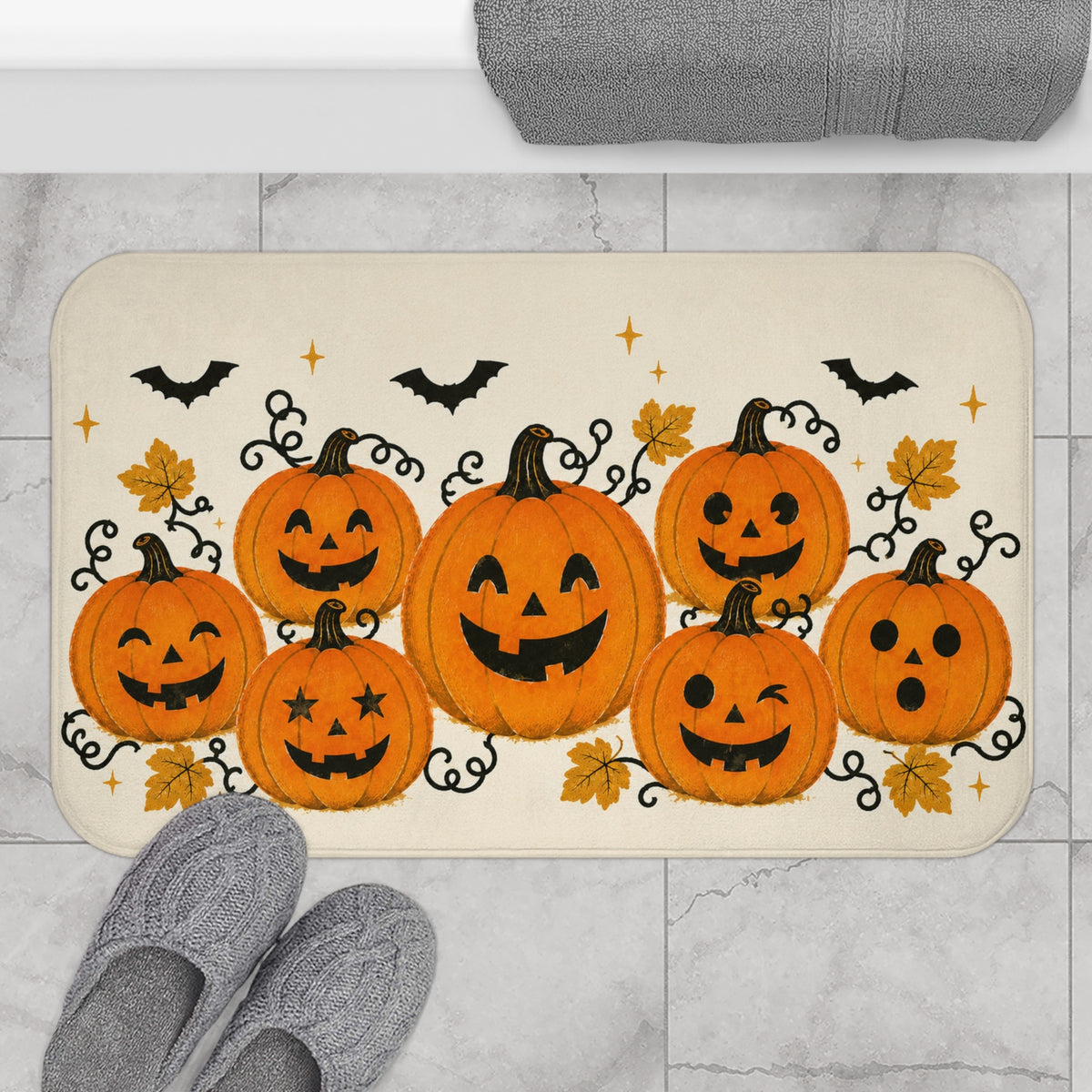 AmazerBath Halloween bath mat featuring orange jack-o'-lantern cluster on cream placed on light bathroom tile beside a bathtub.