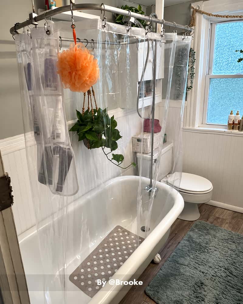 AmazerBath clear 2-pack lightweight 3G PEVA shower curtain liner surrounding a clawfoot tub with a hanging bath sponge.