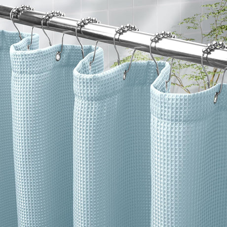 Light blue waffle-textured shower curtain with silver hooks on a metal rod.