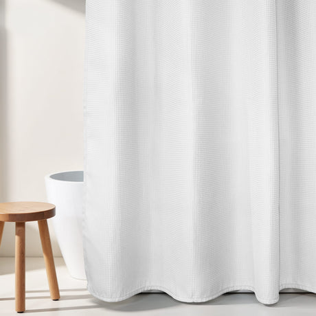 White textured shower curtain with a wooden stool and white container in the background