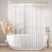 Clear shower curtain with a white bathtub and gold fixtures in a bathroom setting.