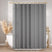 Gray shower curtain hanging in a bathroom with a bathtub and decorative elements.