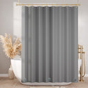 Gray shower curtain hanging in a bathroom with a bathtub and decorative elements.