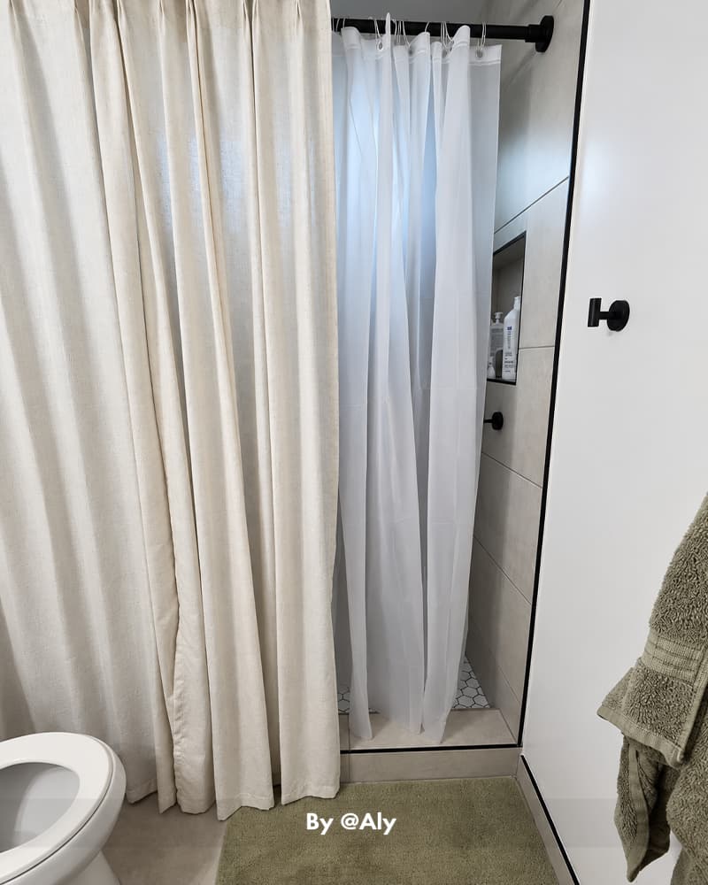 AmazerBath white lightweight 3G PEVA shower curtain liner hanging inside a narrow shower behind a cream outer curtain.