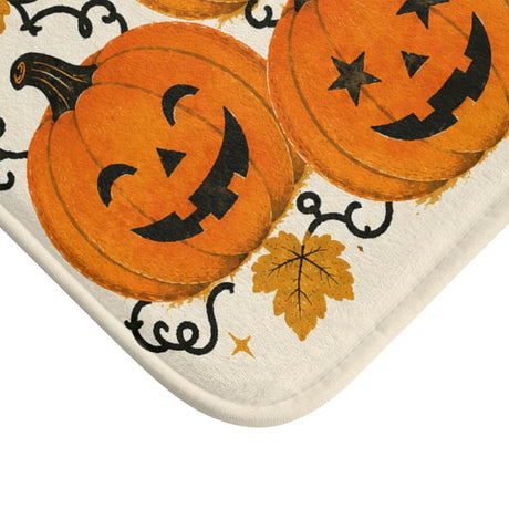 AmazerBath Halloween bath mat corner with orange jack-o'-lantern cluster on cream, vivid print, soft texture, and a bound edge.