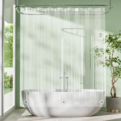 Modern bathroom with a freestanding bathtub, clear shower curtain, and greenery.
