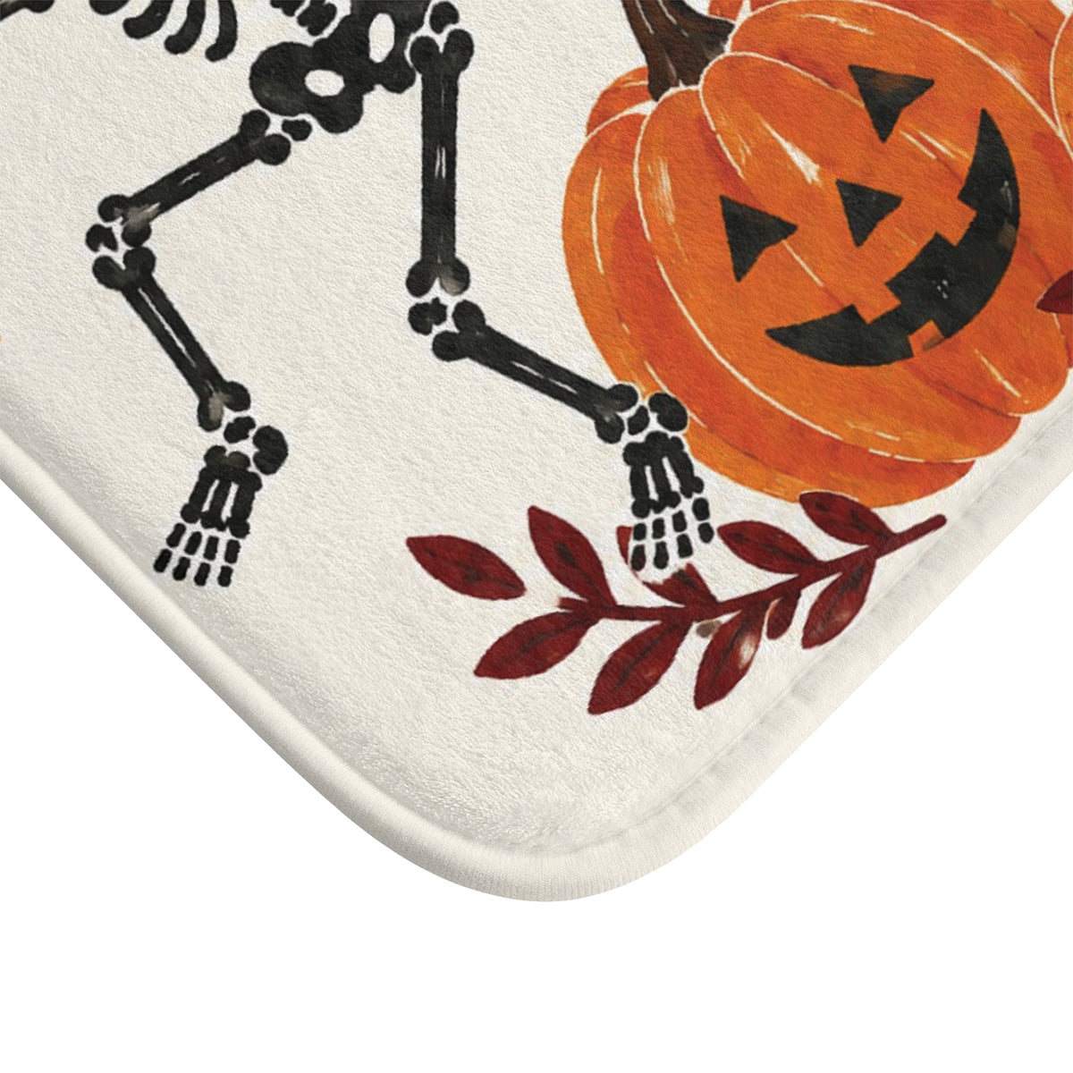 AmazerBath Halloween bath mat corner with dancing skeletons and pumpkins on cream, vivid print, soft texture, and a bound edge.