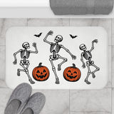 AmazerBath Halloween bath mat featuring dancing skeletons with jack-o'-lanterns placed on light bathroom tile beside a bathtub.