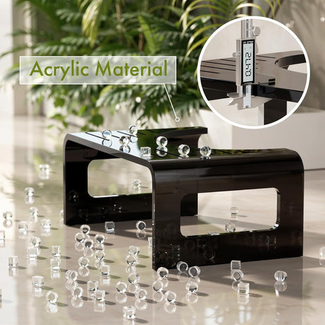 Black acrylic material display with scattered pieces on a reflective surface, indoor plants in the background.