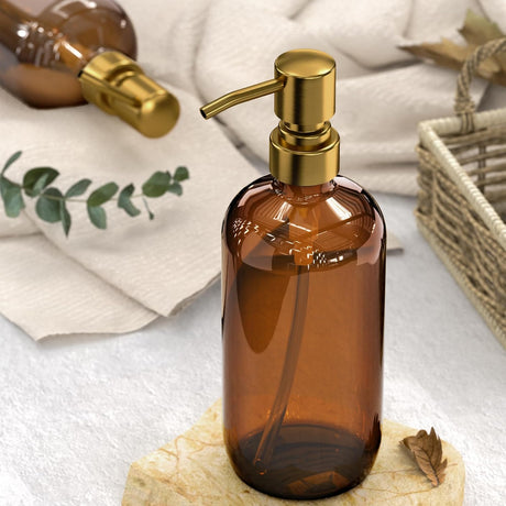 Brown glass bottle with gold pump on a white surface with greenery