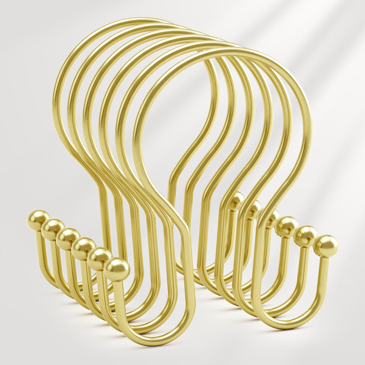 Set of gold metal hooks on a light gray background