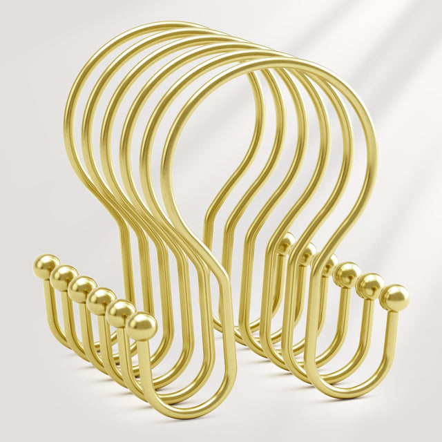 Set of gold metal hooks on a light gray background