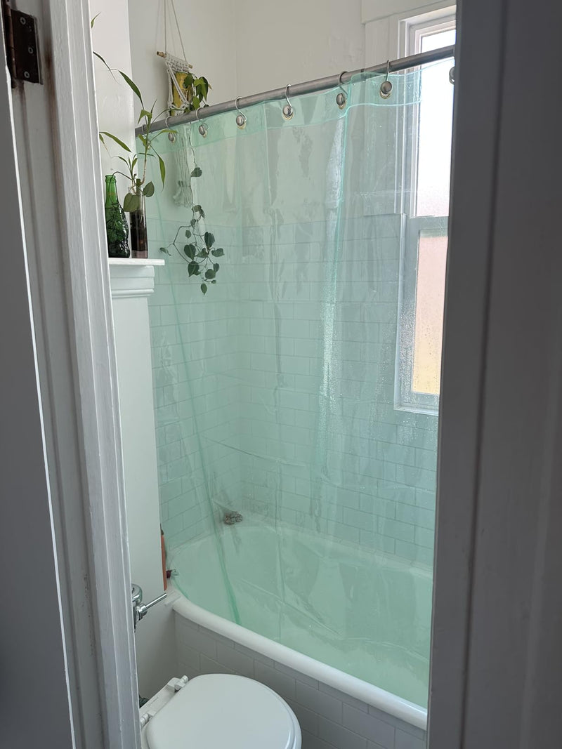 Bathroom with a green shower curtain and plants on a shelf.