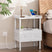 White nightstand with lamp, phone, and books next to a bed