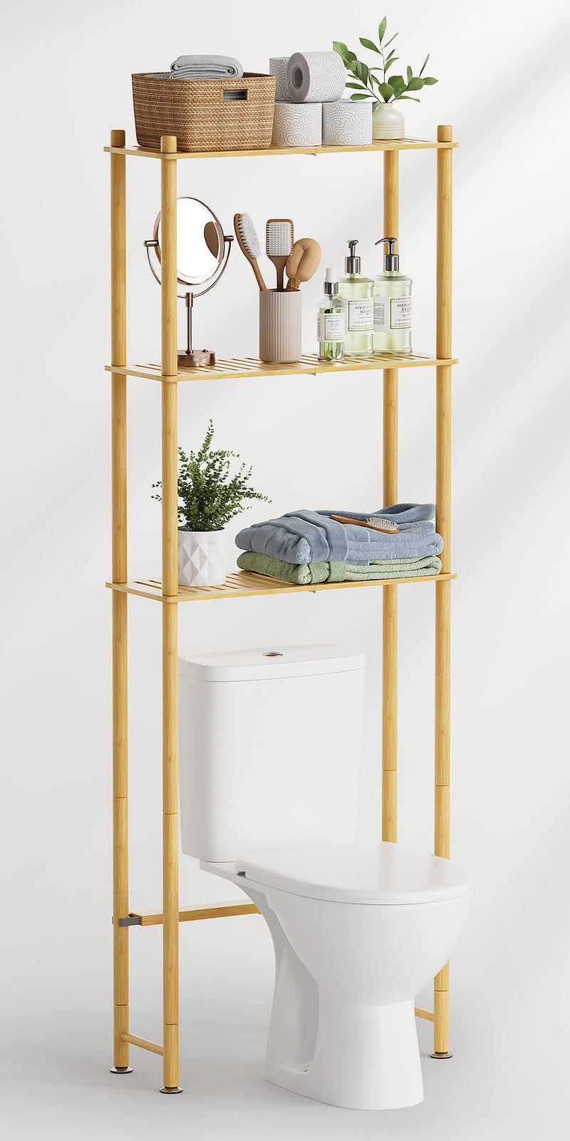 AmazerBath bamboo over-the-toilet storage shelf with three tiers holding towels, toiletries, a mirror, baskets, and plants.