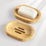 Two bamboo wooden soap dishes with a bar of soap on a light gray background