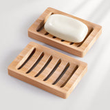 Bamboo soap dish with a bar of soap on a light gray background