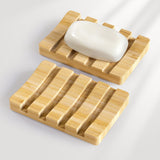 Wooden soap dish with a bar of soap on a light gray background