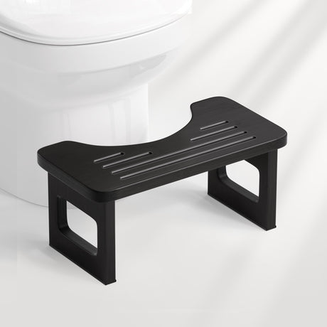 Black step stool in front of a white toilet on a white background