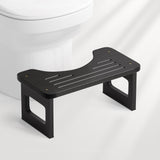 Black bathroom step stool in front of a toilet on a white background