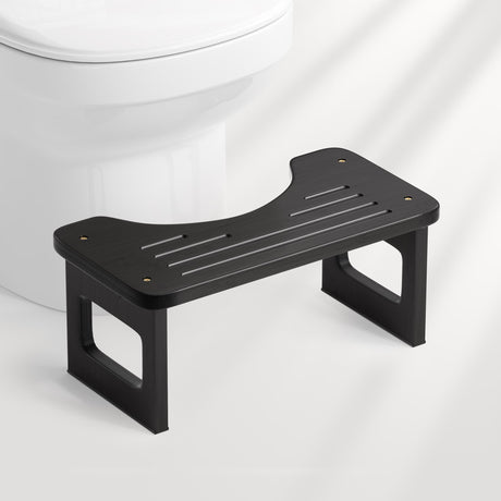 Black bathroom step stool in front of a toilet on a white background