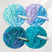 Four mesh bath poufs in blue, purple, and green with 'nazerBath' branding on a light gray background.