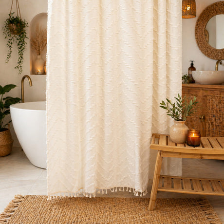 Beige textured shower curtain in a bathroom with a wooden side table and plants.