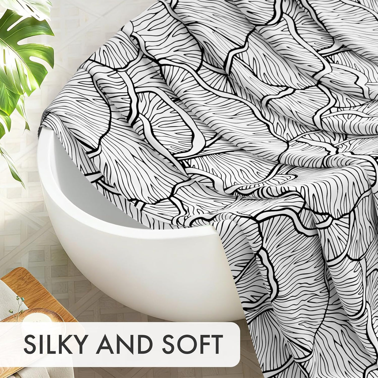 Black and white patterned towel draped over a white bathtub with a plant in the background