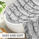 Black and white patterned towel draped over a white bathtub with a plant in the background