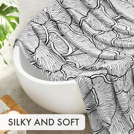 Black and white patterned towel draped over a white bathtub with a plant in the background