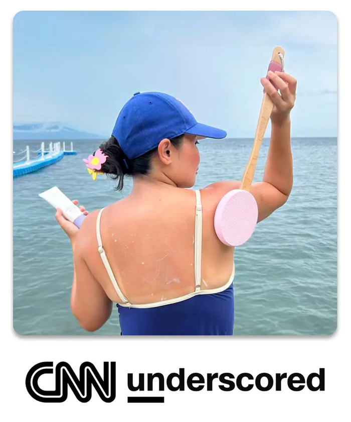 AmazerBath pink long-handle lotion applicator used on the back by a woman at the beach, featured by CNN Underscored
