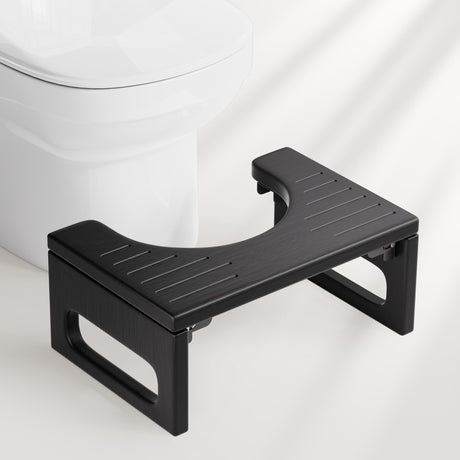Black bathroom step stool in front of a toilet on a white background
