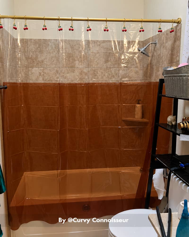 AmazerBath amber color-block Sun EVA shower curtain liner hanging across a tiled bathtub with colorful hooks.
